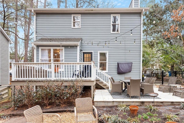 rear view of house featuring outdoor dining space, fence, a chimney, and a wooden deck