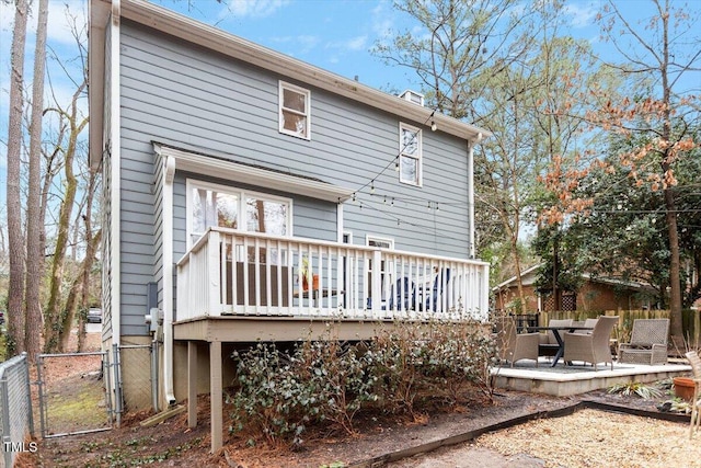 rear view of property featuring a patio, a gate, fence, and a wooden deck