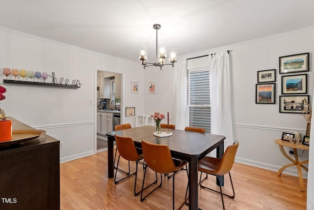 dining space with an inviting chandelier, light wood-style flooring, baseboards, and crown molding