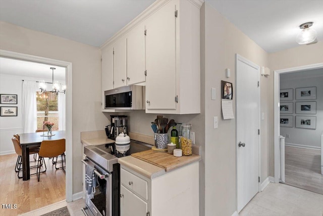 kitchen featuring light wood-style flooring, baseboards, white cabinets, light countertops, and appliances with stainless steel finishes