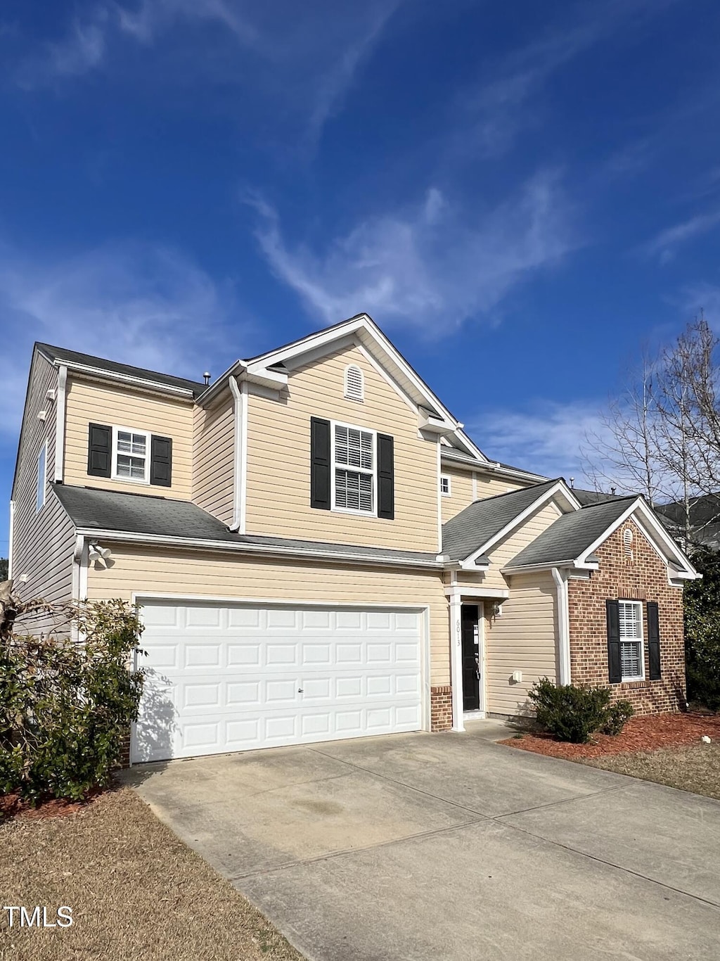 traditional home with concrete driveway, brick siding, and an attached garage