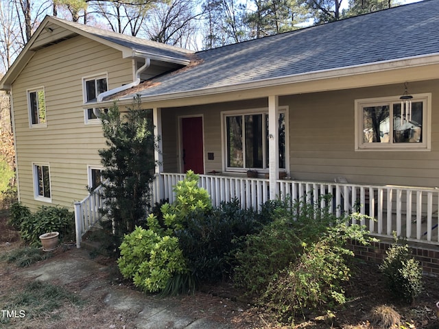 property entrance with covered porch and roof with shingles