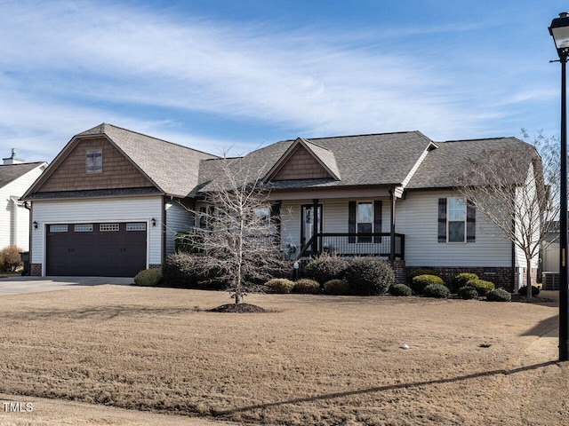 view of front of property with covered porch, concrete driveway, a front lawn, and roof with shingles