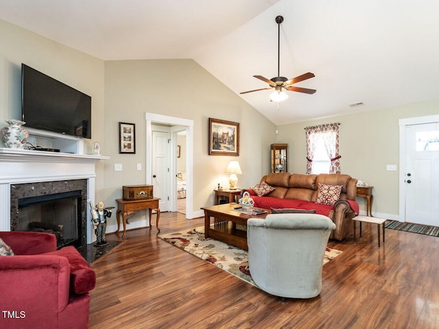 living room with baseboards, lofted ceiling, ceiling fan, a premium fireplace, and wood finished floors