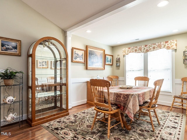 dining area with a wainscoted wall, visible vents, and wood finished floors