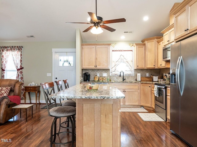 kitchen with appliances with stainless steel finishes, visible vents, a sink, and light brown cabinetry