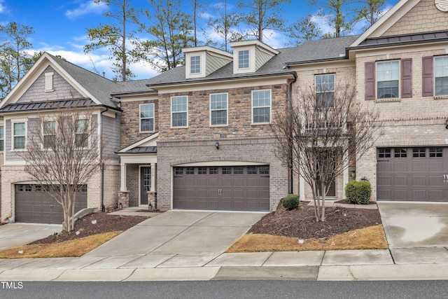 multi unit property featuring brick siding, roof with shingles, concrete driveway, a standing seam roof, and stone siding