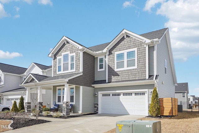 craftsman-style home with an attached garage, covered porch, a shingled roof, fence, and driveway