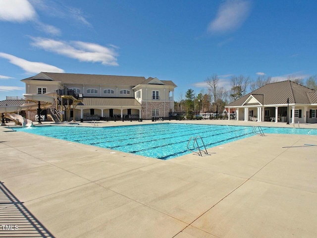 community pool with a water slide and a patio