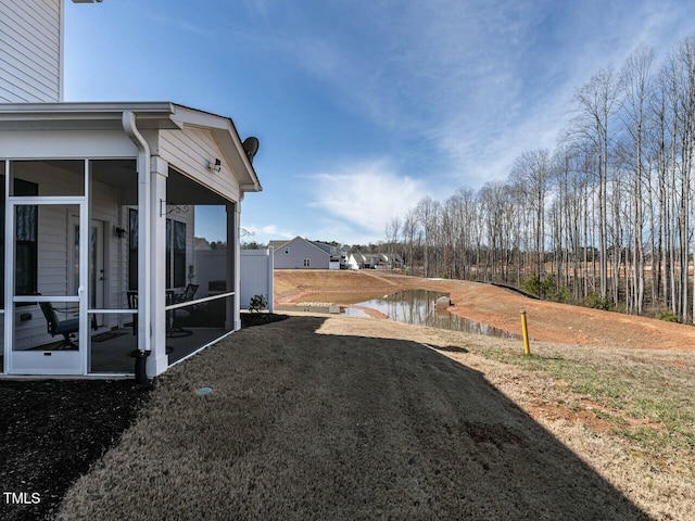 view of yard featuring a water view and a sunroom