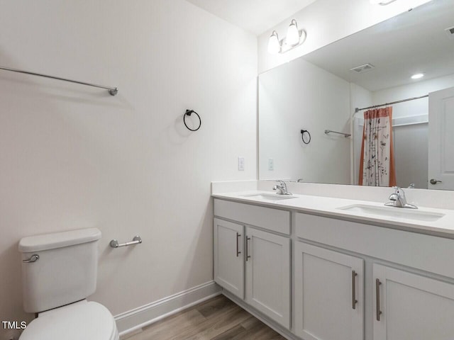 full bath featuring toilet, visible vents, a sink, and wood finished floors