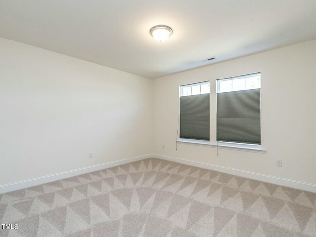 spare room with light carpet, visible vents, and baseboards