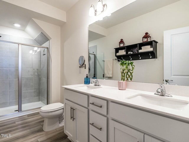 full bathroom featuring a stall shower, a sink, toilet, and wood finished floors