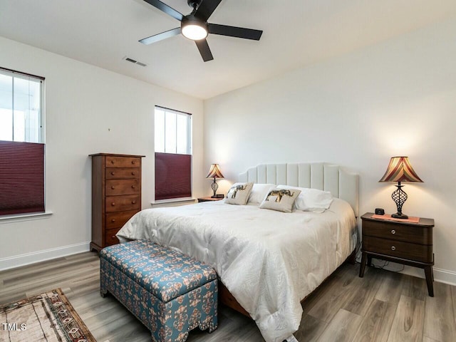 bedroom with a ceiling fan, baseboards, visible vents, and wood finished floors