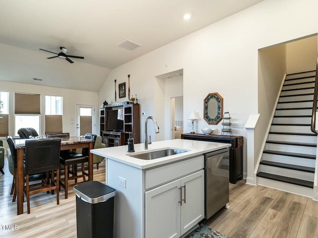 kitchen featuring visible vents, light wood-style flooring, stainless steel dishwasher, open floor plan, and a sink