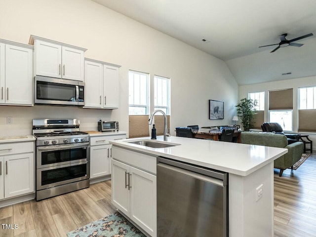 kitchen featuring appliances with stainless steel finishes, open floor plan, light countertops, and a sink