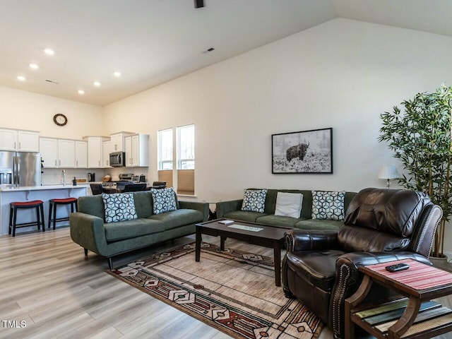 living room with light wood-style flooring, visible vents, high vaulted ceiling, and recessed lighting