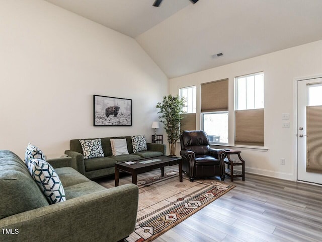 living room featuring visible vents, vaulted ceiling, baseboards, and wood finished floors