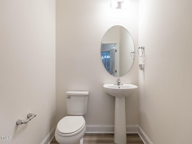 bathroom with a sink, toilet, baseboards, and wood finished floors