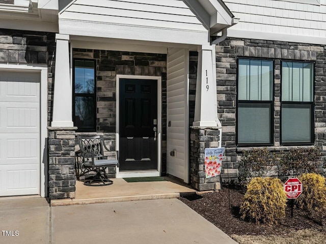 doorway to property featuring a garage and stone siding