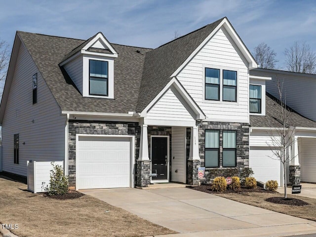 view of front facade with stone siding, roof with shingles, and concrete driveway