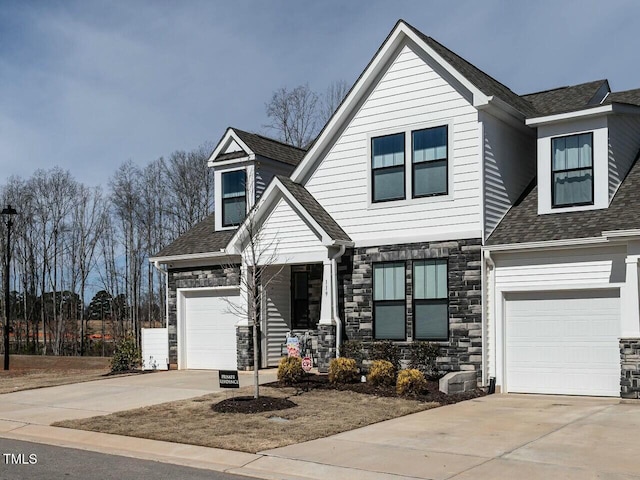 view of front of home featuring a garage, stone siding, roof with shingles, and concrete driveway