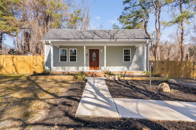 view of front of home featuring covered porch, roof with shingles, fence, and a gate