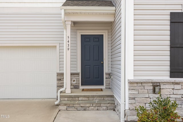 entrance to property with stone siding and roof with shingles