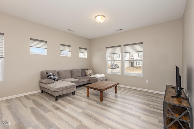 living area featuring visible vents, light wood-style flooring, and baseboards