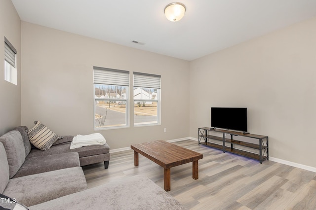 living room with light wood-style floors, baseboards, and visible vents