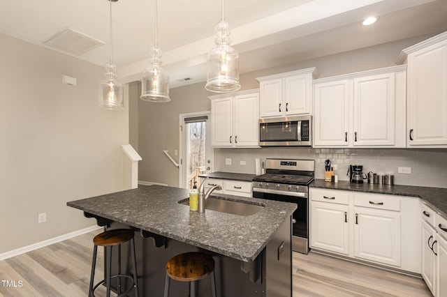 kitchen with white cabinetry, decorative backsplash, stainless steel appliances, and a sink