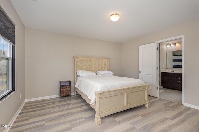 bedroom featuring a sink, light wood finished floors, connected bathroom, and baseboards