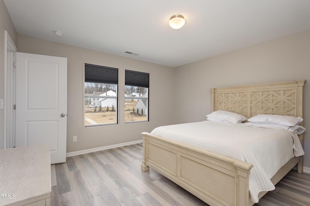 bedroom with baseboards, visible vents, and light wood-style floors