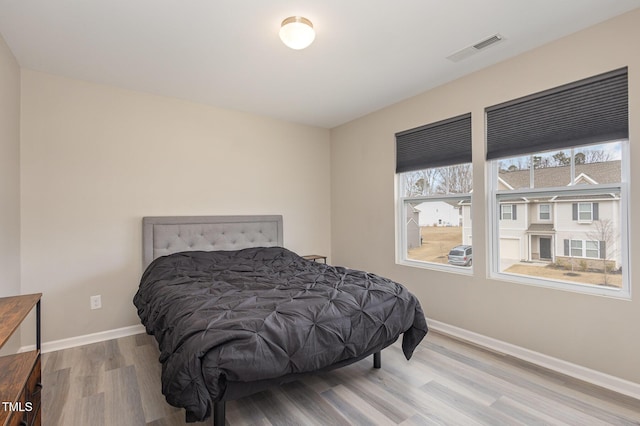 bedroom featuring visible vents, baseboards, and wood finished floors