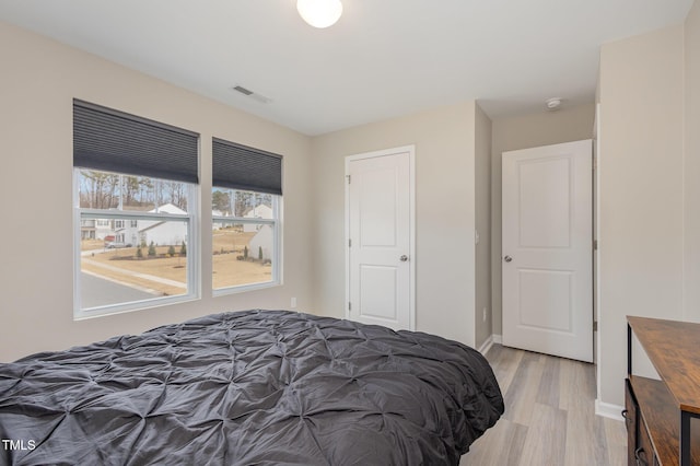 bedroom featuring light wood-type flooring, visible vents, and baseboards