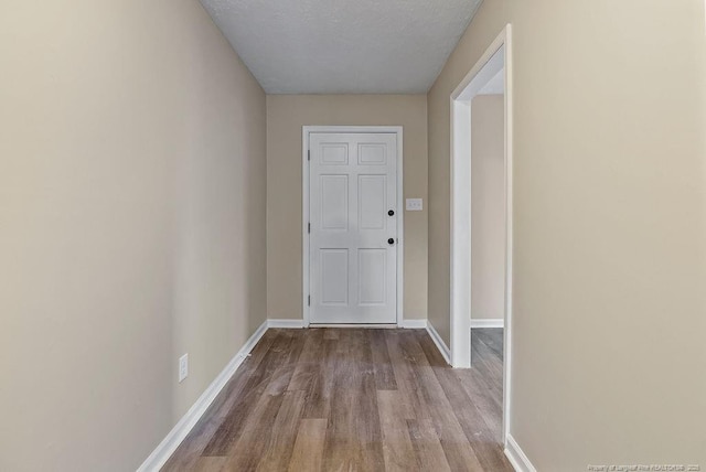 doorway featuring baseboards and wood finished floors