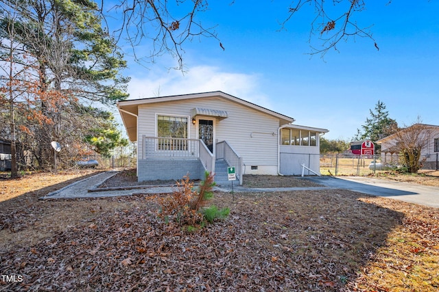 view of front facade with crawl space, fence, and concrete driveway