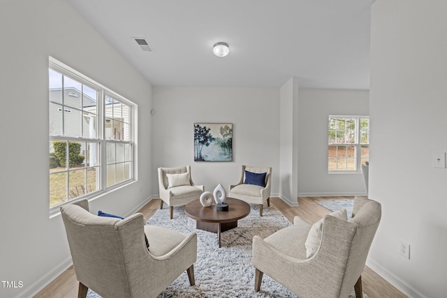 living area with light wood-style flooring, visible vents, and baseboards