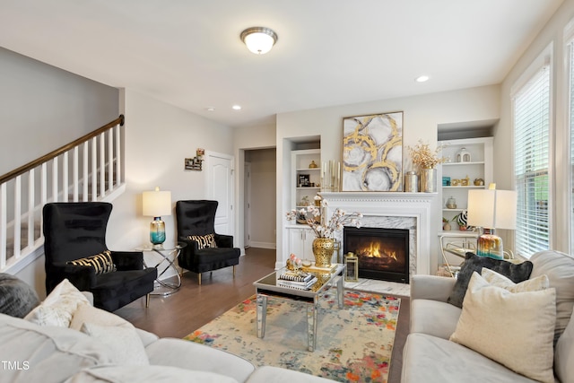 living area featuring built in features, wood finished floors, stairs, a fireplace, and recessed lighting