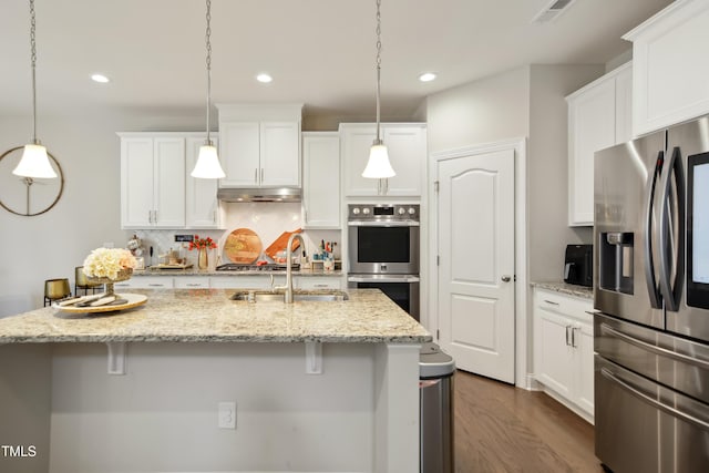 kitchen featuring under cabinet range hood, a sink, visible vents, appliances with stainless steel finishes, and decorative backsplash