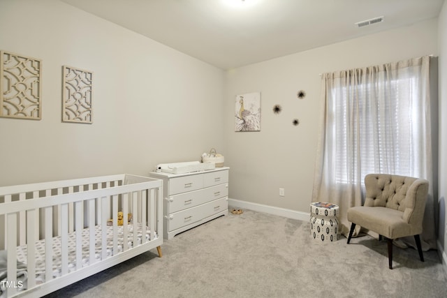 bedroom featuring carpet floors, a nursery area, baseboards, and visible vents