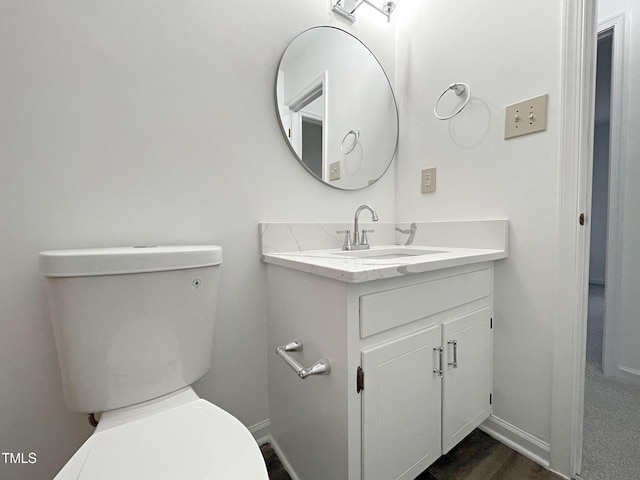 half bathroom with toilet, baseboards, and vanity