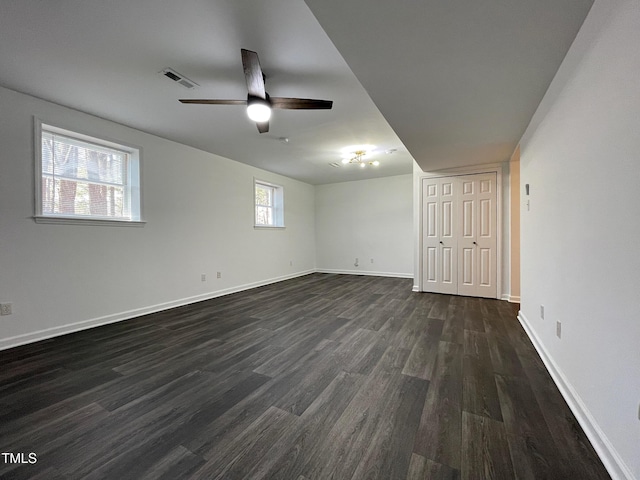 empty room featuring baseboards, visible vents, dark wood finished floors, and a ceiling fan