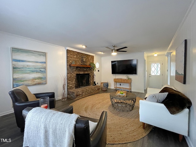 living room with a brick fireplace, crown molding, baseboards, and wood finished floors