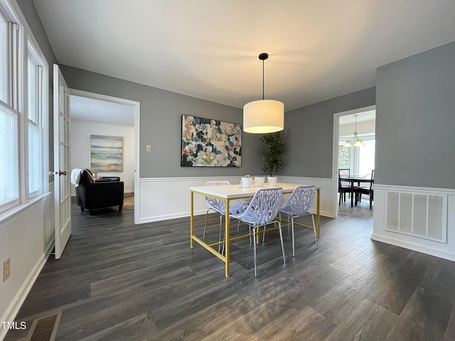 dining space with dark wood-style flooring, visible vents, and baseboards