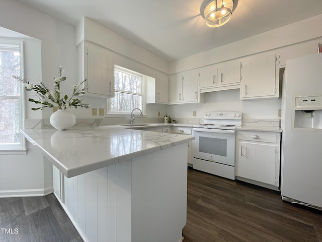 kitchen with white appliances, white cabinets, dark wood-style flooring, a peninsula, and a sink