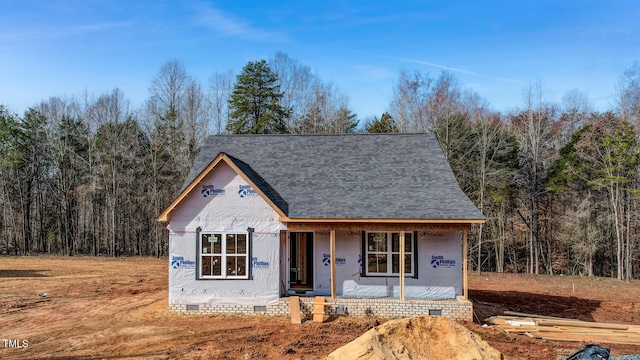 property in mid-construction with crawl space, covered porch, a forest view, and roof with shingles