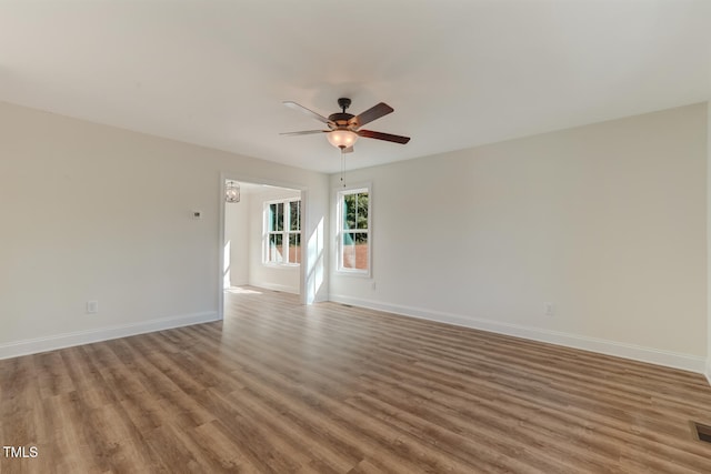 empty room featuring ceiling fan, wood finished floors, visible vents, and baseboards