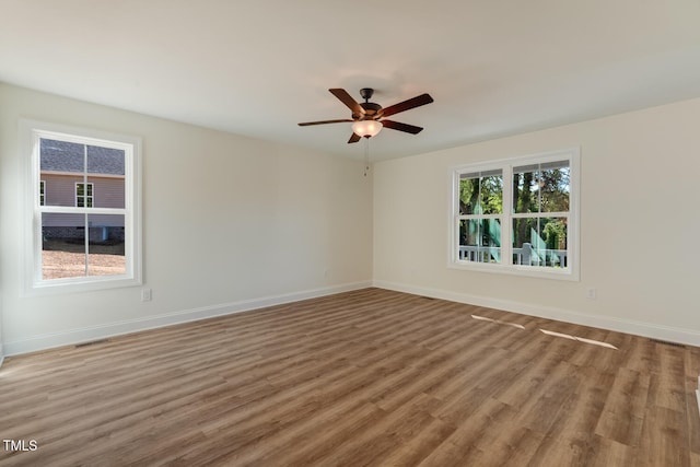 spare room featuring ceiling fan, wood finished floors, visible vents, and baseboards