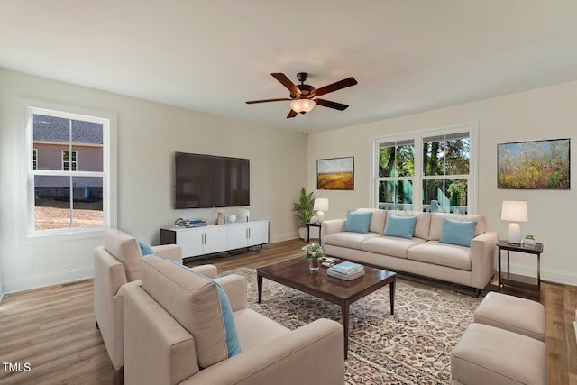 living room with a ceiling fan, light wood-style flooring, and baseboards